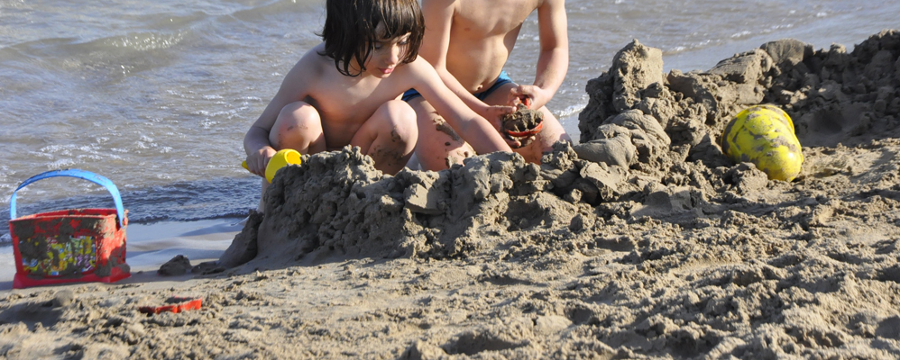 Uns nens juguen a la platja del far de Vilanova