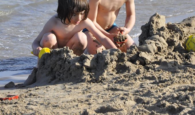 Uns nens juguen a la platja del far de Vilanova